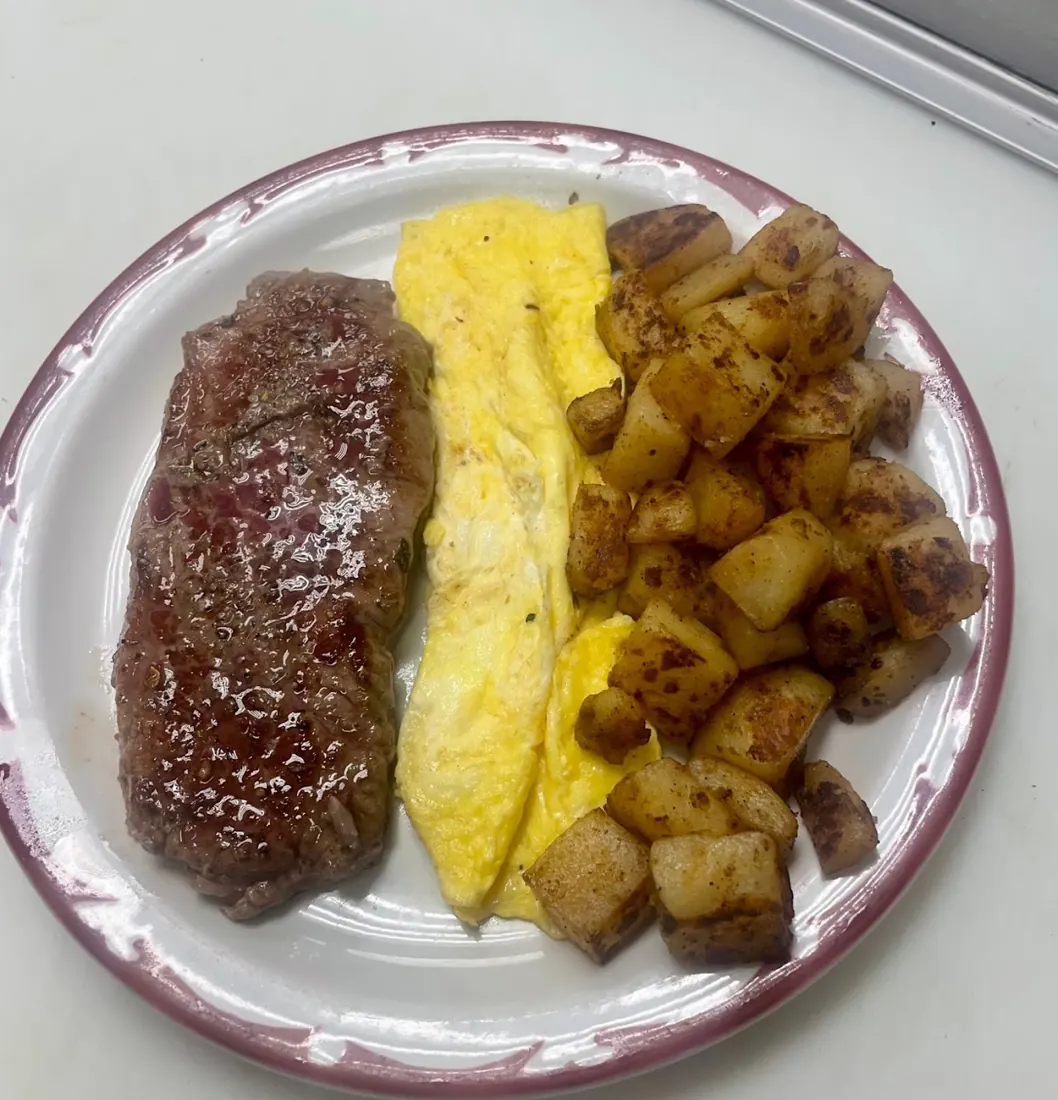 Plate of steak, folded eggs and diced pan-fried potatoes